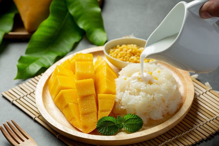 Một đĩa xôi xoài Thái Lan với xoài nam dok mai vàng ươm, xôi nếp dẻo, và nước cốt dừa béo ngậy, rắc mè rang thơm lừng.